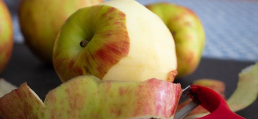 Pommes sur une planche à découper et éplucheur.