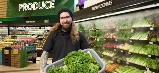 Employé de Sobeys tenant un bac de laitue devant un mur mouillé